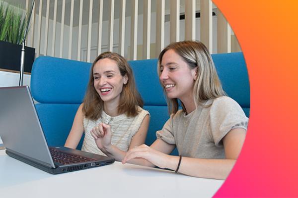 Two girls working together on a laptop computer.